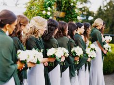 a group of women standing next to each other holding bouquets in their hands and wearing green jackets