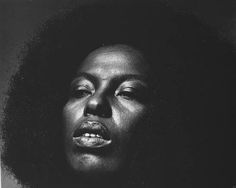 a black and white photo of a woman's face with an afro hairdo