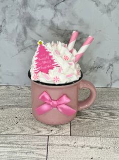 a pink coffee cup filled with whipped cream and candy canes