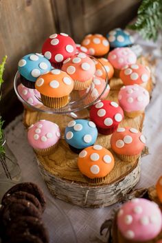 some cupcakes are sitting on top of a wooden slice with white polka dots