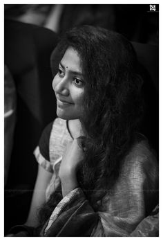 a black and white photo of a woman with long dark hair smiling at the camera