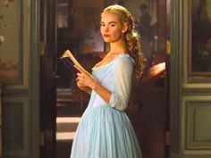 a woman in a blue dress holding a book