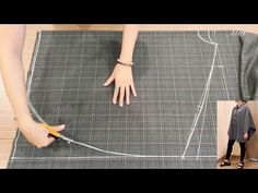 a woman is cutting fabric with scissors on the floor and another person standing next to her