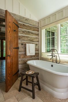 an old fashioned bathtub sits in the middle of a rustic bathroom with wood walls and flooring