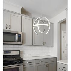 a modern kitchen with stainless steel appliances and white subway backsplashes, including an oval pendant light over the stove