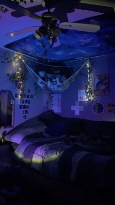 a bed room with a ceiling fan and pictures on the wall above it at night