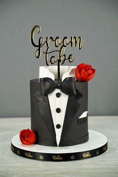 a black and white cake with a red rose on the top that says groom to be