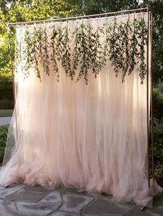 an outdoor wedding ceremony with pink tulle and greenery hanging from the ceiling,