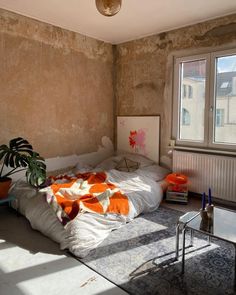 a bed sitting in the middle of a room next to a window and a potted plant