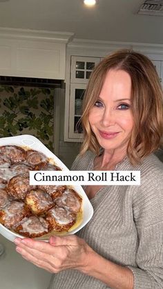 a woman is holding a tray of cinnamon roll hacks