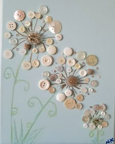 a painting with buttons on it and a flower in the middle is hanging on a wall