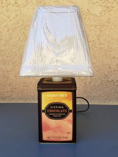 a lamp that is sitting on top of a blue table with a brown tin can underneath it