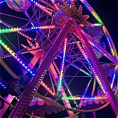 a ferris wheel lit up at night with colorful lights