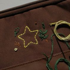 a pair of scissors sitting on top of a brown piece of cloth with green thread