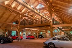 two cars are parked in a large garage with high ceilings and wooden beams on the ceiling