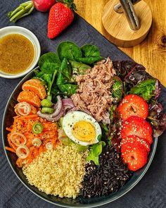 a plate filled with meat, vegetables and rice next to dipping sauce on a table