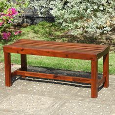 a wooden bench sitting on top of a sidewalk next to a flower filled garden area