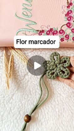 someone is holding a crochet flower in front of a pink bag with the words flor marcador on it