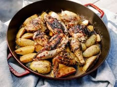 chicken and potatoes cooking in a skillet on a table top with a blue towel