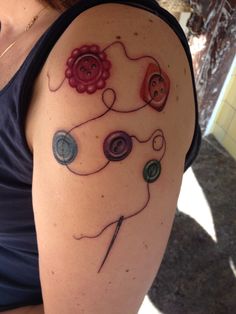 a woman with a tattoo on her arm has buttons and flowers in the shape of a heart