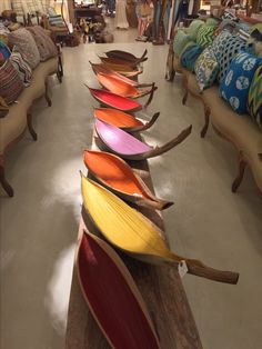 a row of colorful vases sitting on top of a wooden table next to couches