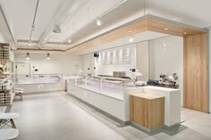 an empty store filled with lots of counter space and white counters topped with wooden shelves