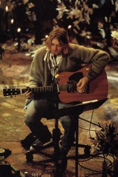 a man sitting on top of a chair holding a guitar