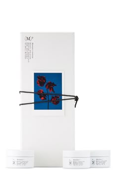 three white boxes with red flowers on them and some black string wrapped around the edges