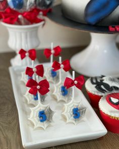 red, white and blue cupcakes on a plate with spiderman toppers