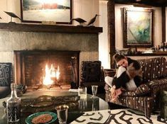 a woman sitting in a chair next to a fire place