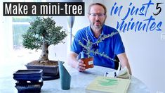 a man sitting at a table with a book and a bonsai tree in front of him