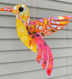 a colorful hummingbird hanging from a string on a house's front door window