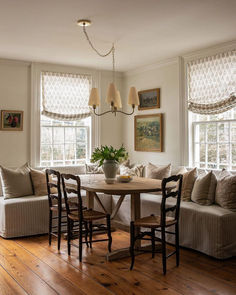 a dining room table with chairs around it and a couch in the corner by the window