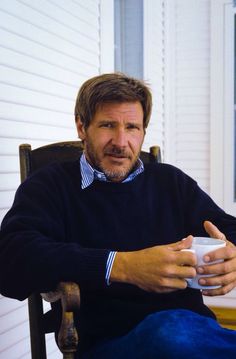 a man sitting in a chair holding a coffee cup