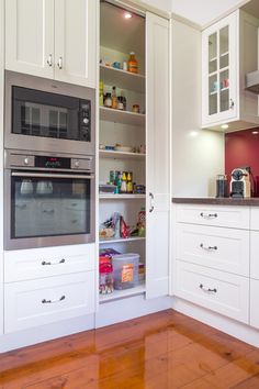 a kitchen with white cabinets and wood flooring has an oven, microwave, and toaster in it