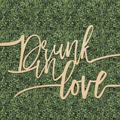 the words drunk love are placed on top of a green wall covered in ivy leaves