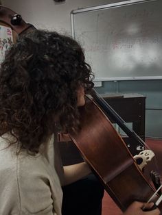 a woman playing an instrument in front of a whiteboard