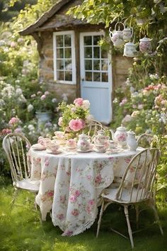 a table with flowers on it in front of a small building and some chairs outside