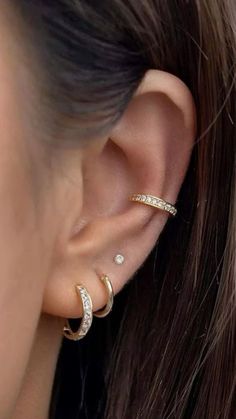 a woman wearing gold ear piercings with white stones