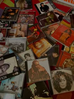 a pile of various cd's laying on top of each other in front of a red wall