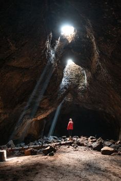 a person standing in the middle of a cave with light coming from their headlight