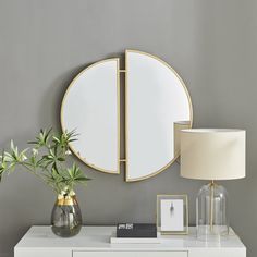 a white dresser topped with a mirror next to a lamp and vase filled with flowers