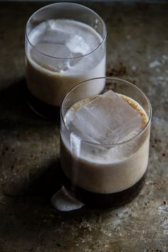 two glasses filled with ice sitting on top of a table