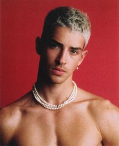 a shirtless man wearing a pearl necklace