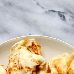 some food is on a white plate and sits on a marble counter top with a gray background