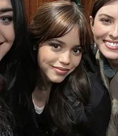 three girls are smiling and posing for the camera