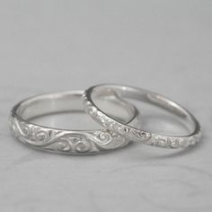 two silver wedding rings sitting next to each other