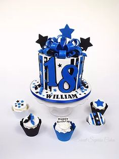 a blue and white birthday cake surrounded by cupcakes