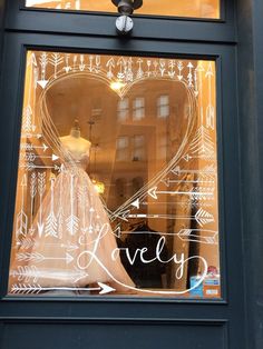 a dress is drawn on the glass in front of a storefront window that says lovely