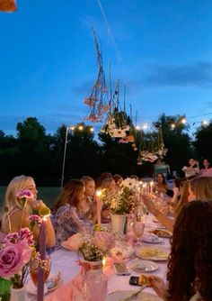 a group of people sitting around a table with food and candles in front of them